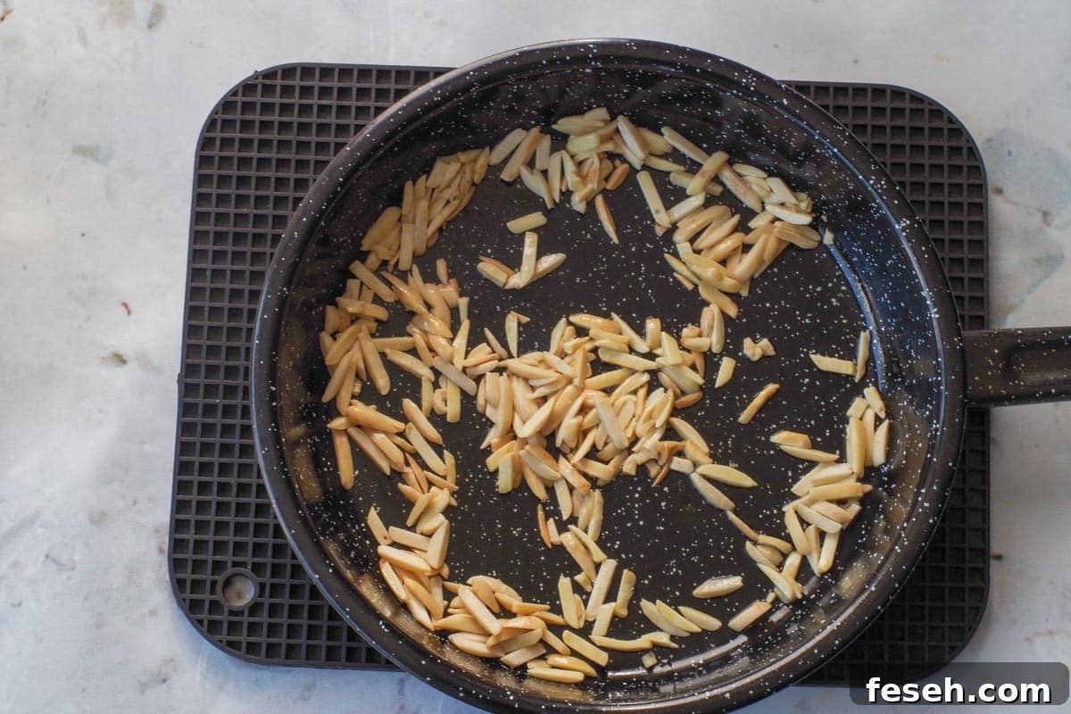 Almonds being toasted in frying pan with oil.