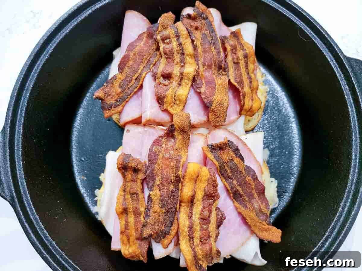 ham slices and cooked bacon slices added to two slices of rye bread in a cast iron skillet.