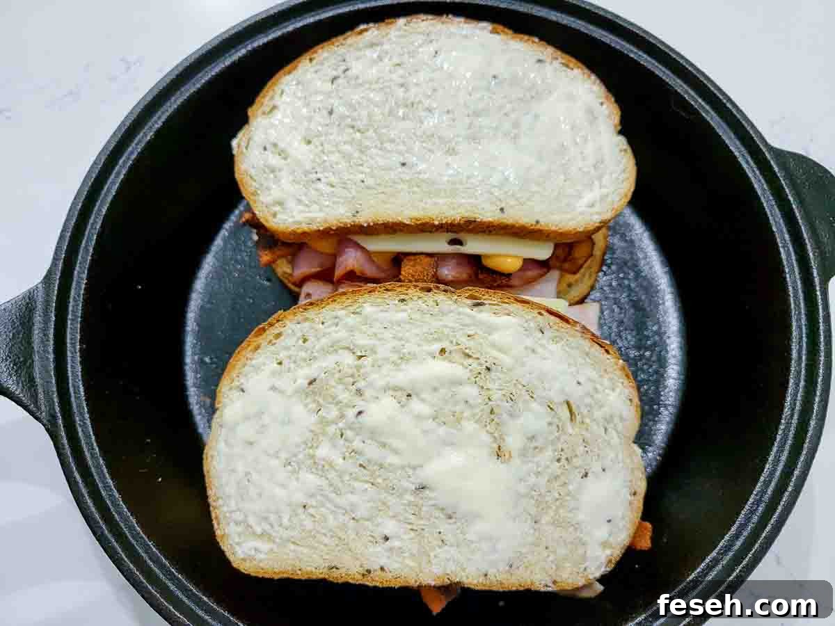 bacon Rueben sandwiches cooking in a cast iron skillet.