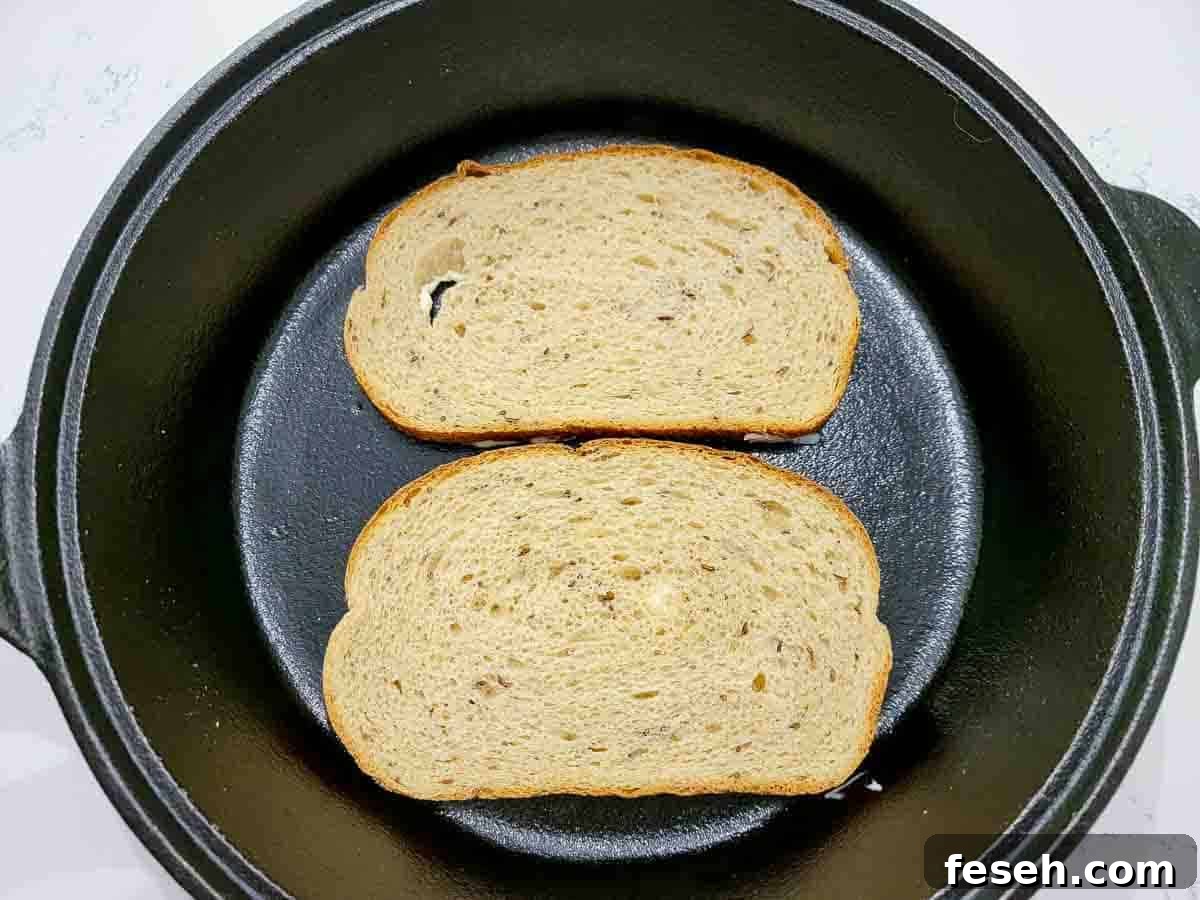 two slices of rye bread in a cast iron skillet buttered side down.