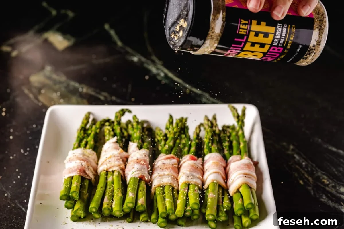 A chef's hand sprinkling Hey Grill Hey Beef Rub onto a white plate topped with veggies in a bacon wrap.