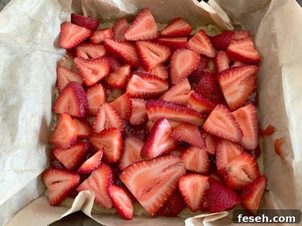 The sliced strawberries on the crust layer.