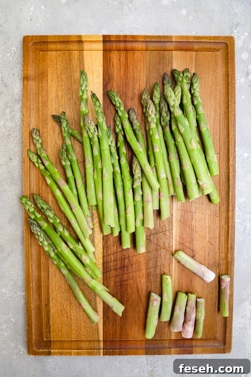 Fresh asparagus sitting on a wood cutting board with the woody ends trimmed off