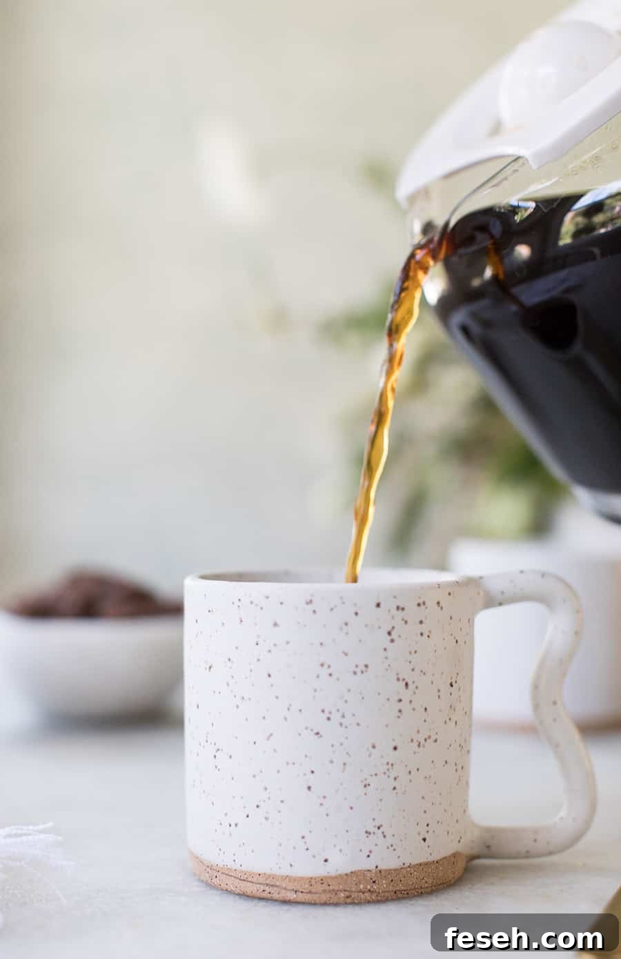 side shot of coffee being poured into a mug
