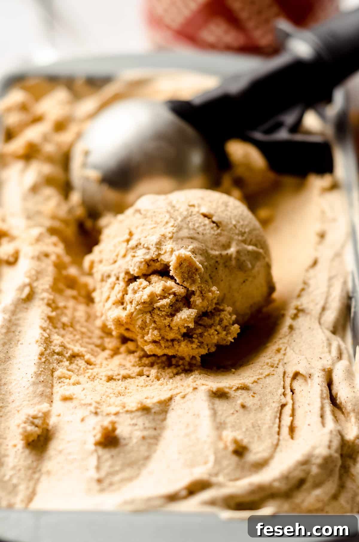 a scoop of pumpkin ice cream with an ice cream scooper in the background