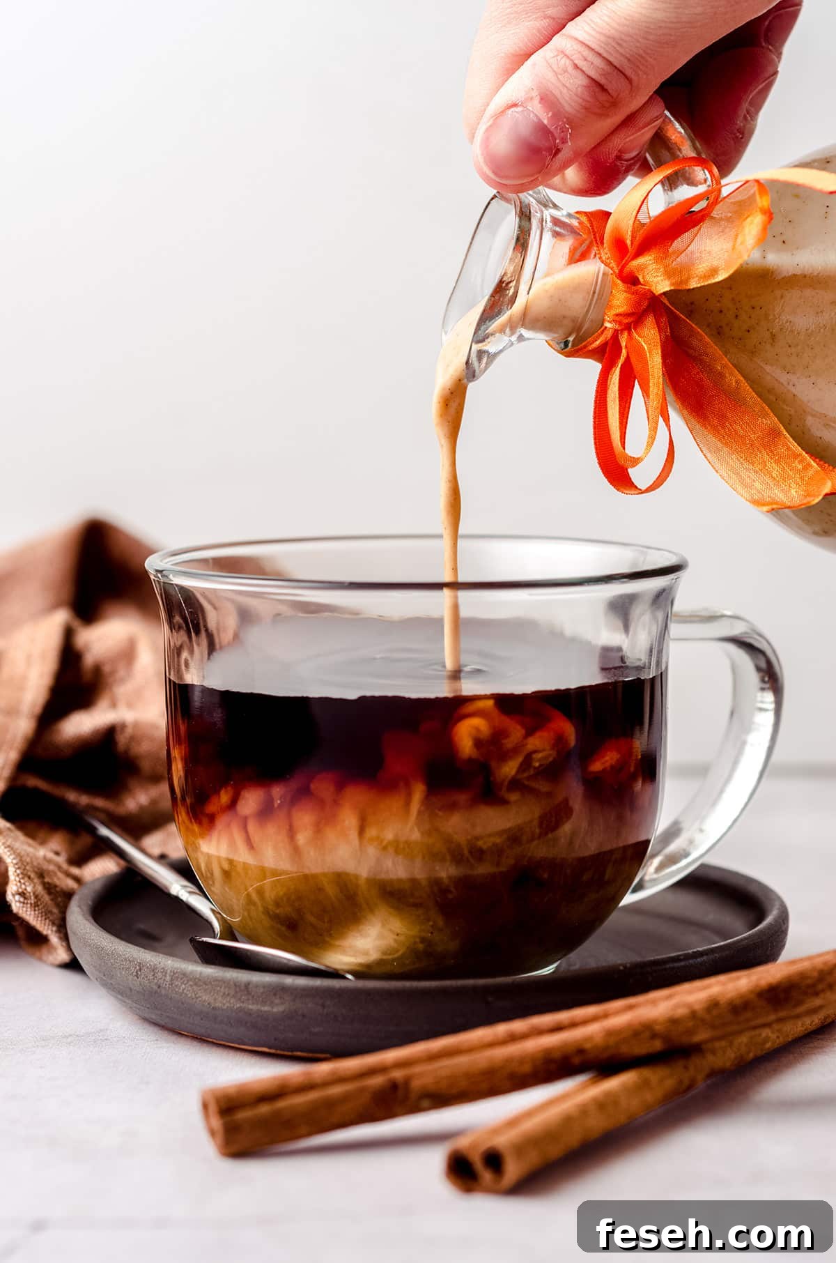 pouring pumpkin spice creamer into a cup of coffee