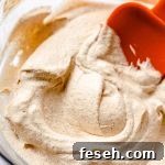 pumpkin spice whipped cream in a bowl spread around with an orange spatula