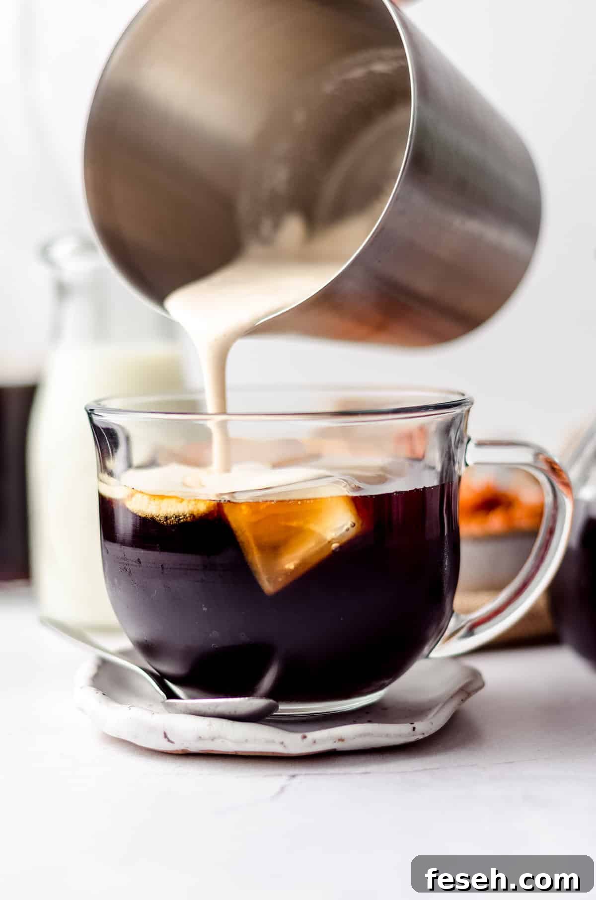 pouring pumpkin cold foam from a frother onto cold brewed coffee
