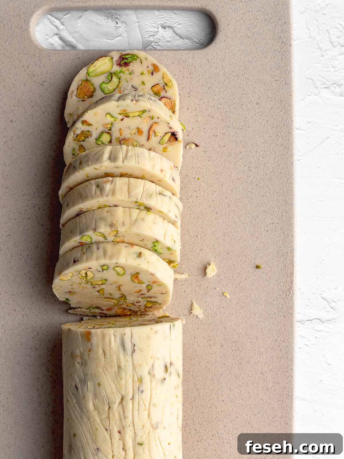 A log of pistachio shortbread cookie dough cut into slices.