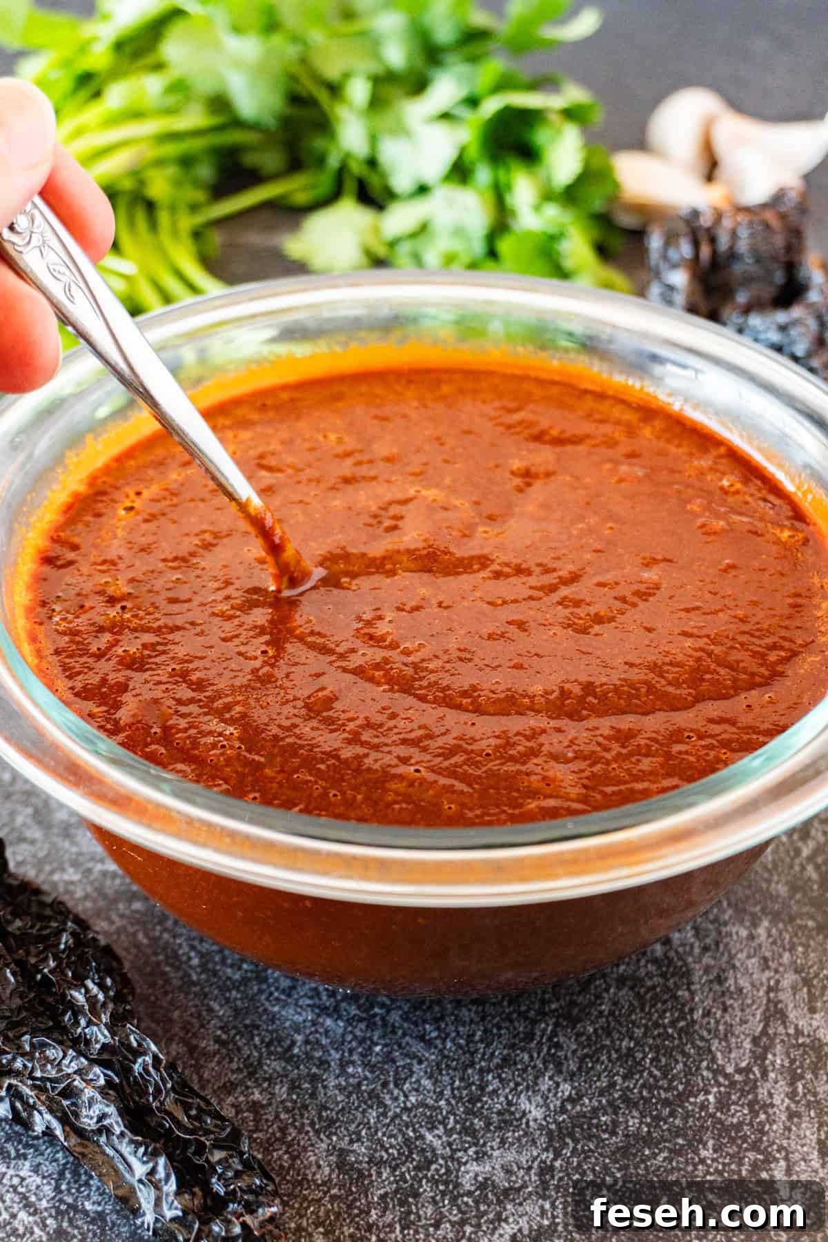 stirring red enchilada sauce with metal spoon.