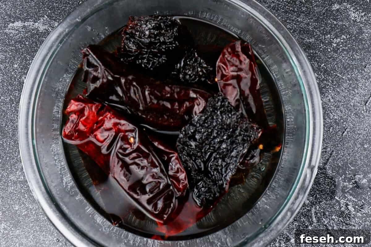 soaking roasted dried chiles in water in clear glass bowl.