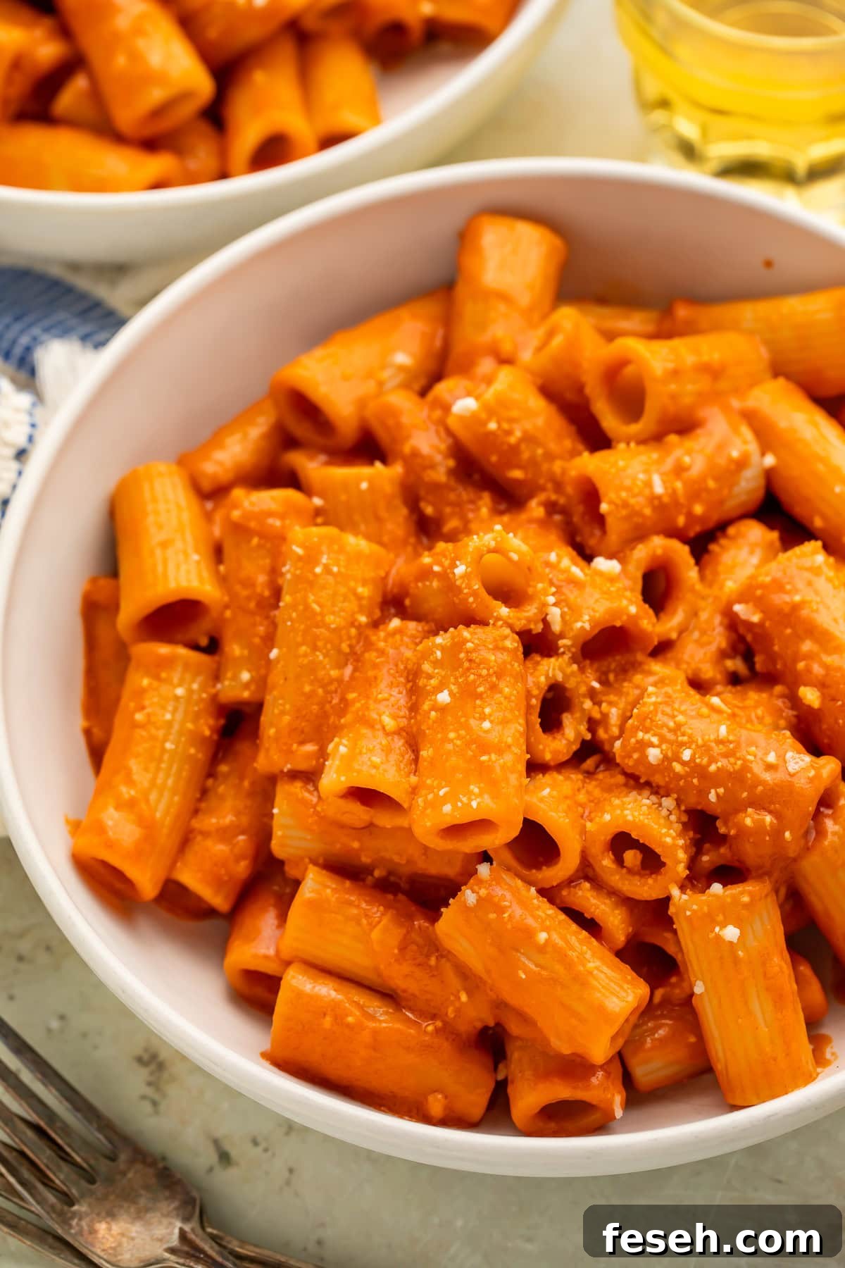 Close up of a white bowl of rigatoni pasta tossed with vegan vodka pasta sauce.