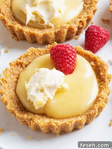 A lemon curd tartlet topped with raspberries and cream.