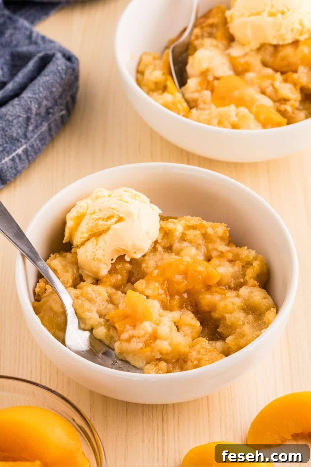 Two white bowls filled with servings of peach cobbler made with canned peaches and cake mix.