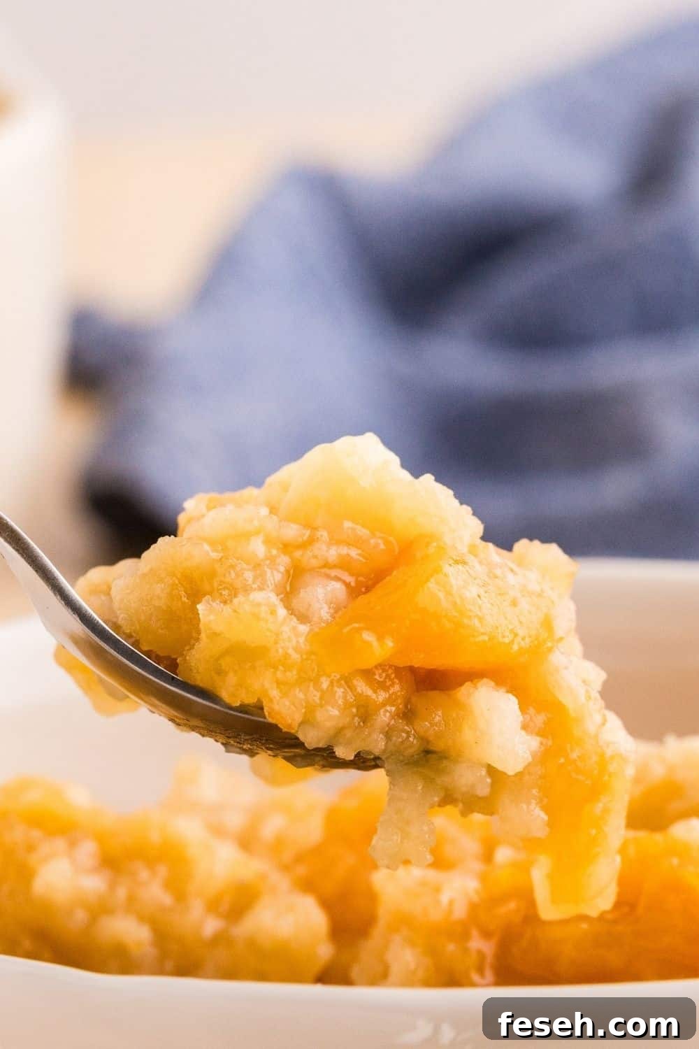 Close up view of a spoon that lifts out a bite of peach dump cake made with canned peaches.