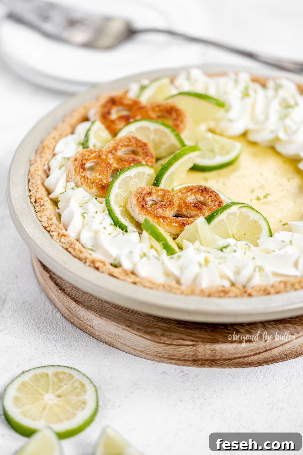 Easy Key Lime Pie decorated with homemade whipped cream, puff pastry twists, and sliced limes | Image and Copyright Policy: © Beyond the Butter, LLC