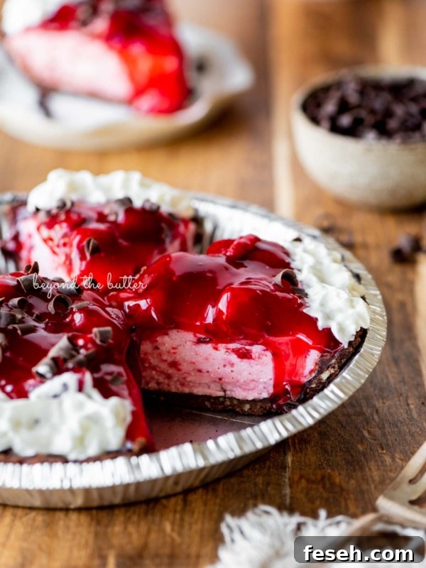 Sliced no bake strawberry chocolate cream pie on wood table with a fork and small bowl of chocolate curls nearby.