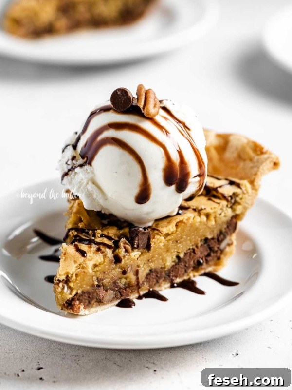 Angled closeup image of Chocolate Chip Pie with a scoop of vanilla ice cream on top that's drizzled with chocolate syrup.