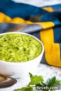 Chimichurri sauce in a white bowl with a blue cloth in the background.
