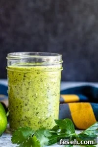 Chimichurri sauce in a glass mason jar with herbs next to it.