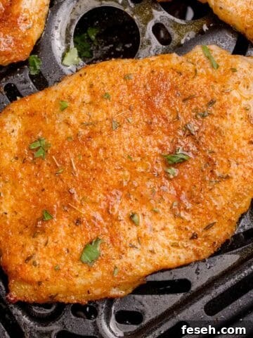 A cooked and seasoned thin pork chop in the air fryer basket.
