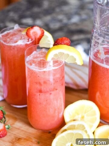 Glasses of strawberry lemonade topped with sliced fruit.