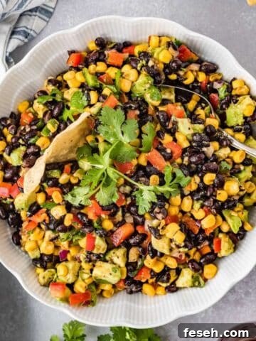 Cowboy caviar dip with black beans, corn, avocado, and tortilla chips in a serving bowl.