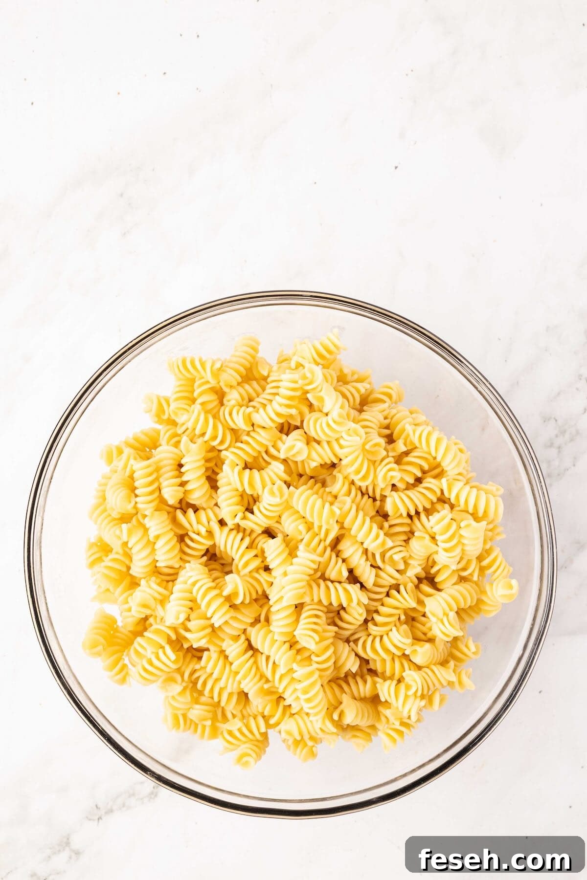 Cooked rotini pasta in a glass bowl.
