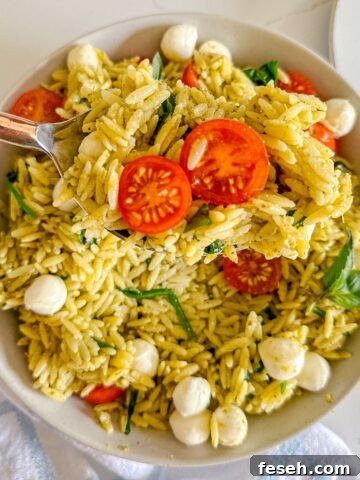 Pesto pasta salad with a serving taken out of it and a large spoon.