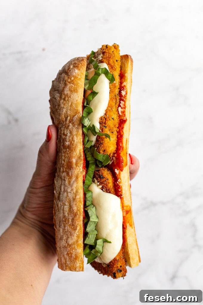 Woman's hand holding a Tofu Parmesan Sandwich.