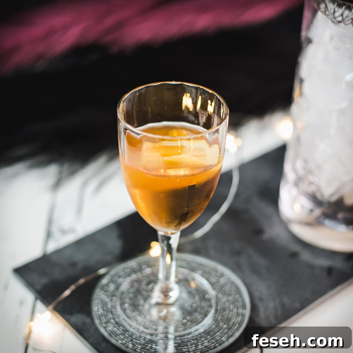 Glass filled with a delicious Martinez cocktail, garnished with a lemon zest.