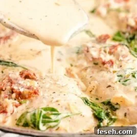 close up shot of a skillet full of Tuscan Chicken with a spoonful of sauce
