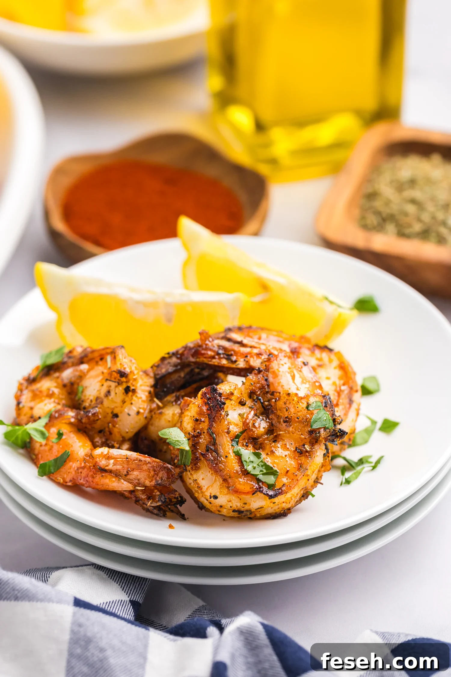 Close-up of grilled shrimp served on a white plate with lemon wedges and garnished with chopped parsley.