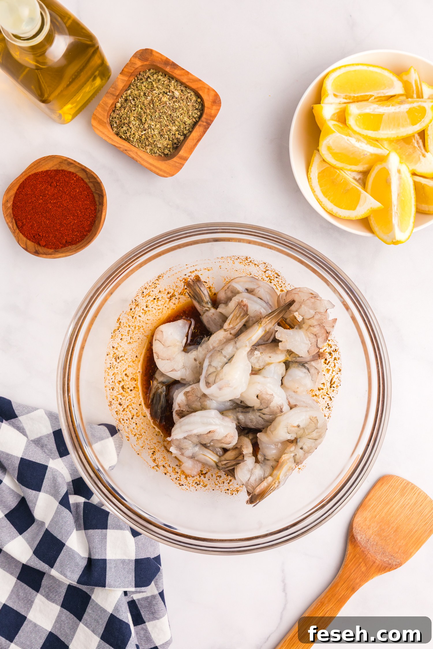 Raw shrimp added to the bowl with the marinade, ready to be tossed.