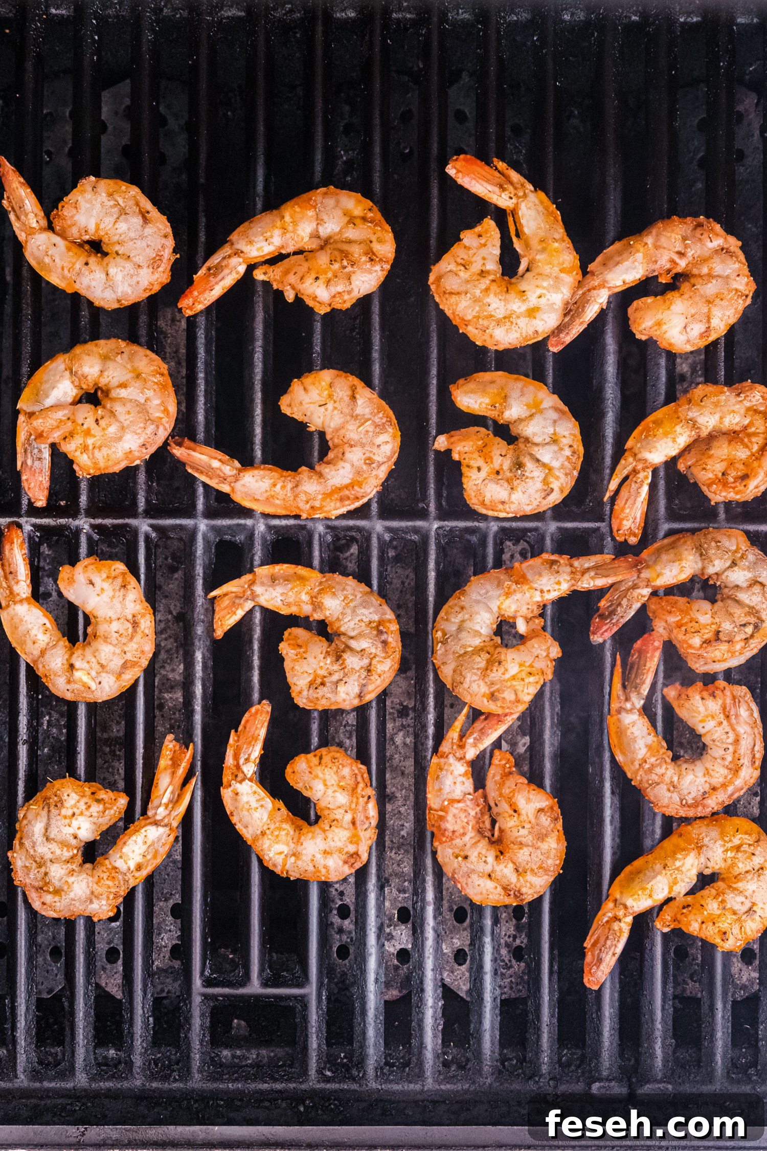 Marinated shrimp placed on a hot grill, beginning to cook with a light sear.