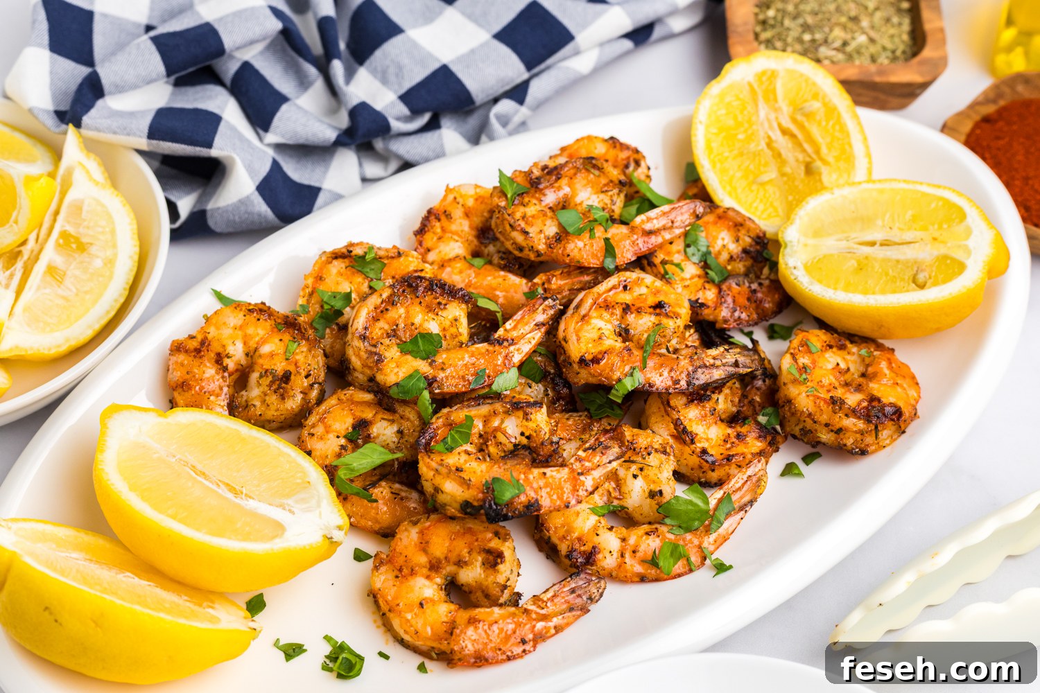 Final plated presentation of grilled shrimp on a white platter, garnished with fresh parsley and surrounded by lemon wedges.