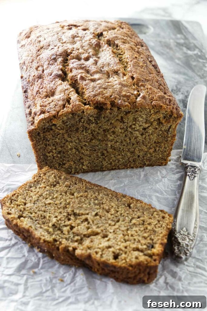 A knife next to a loaf of whole wheat spelt banana bread.