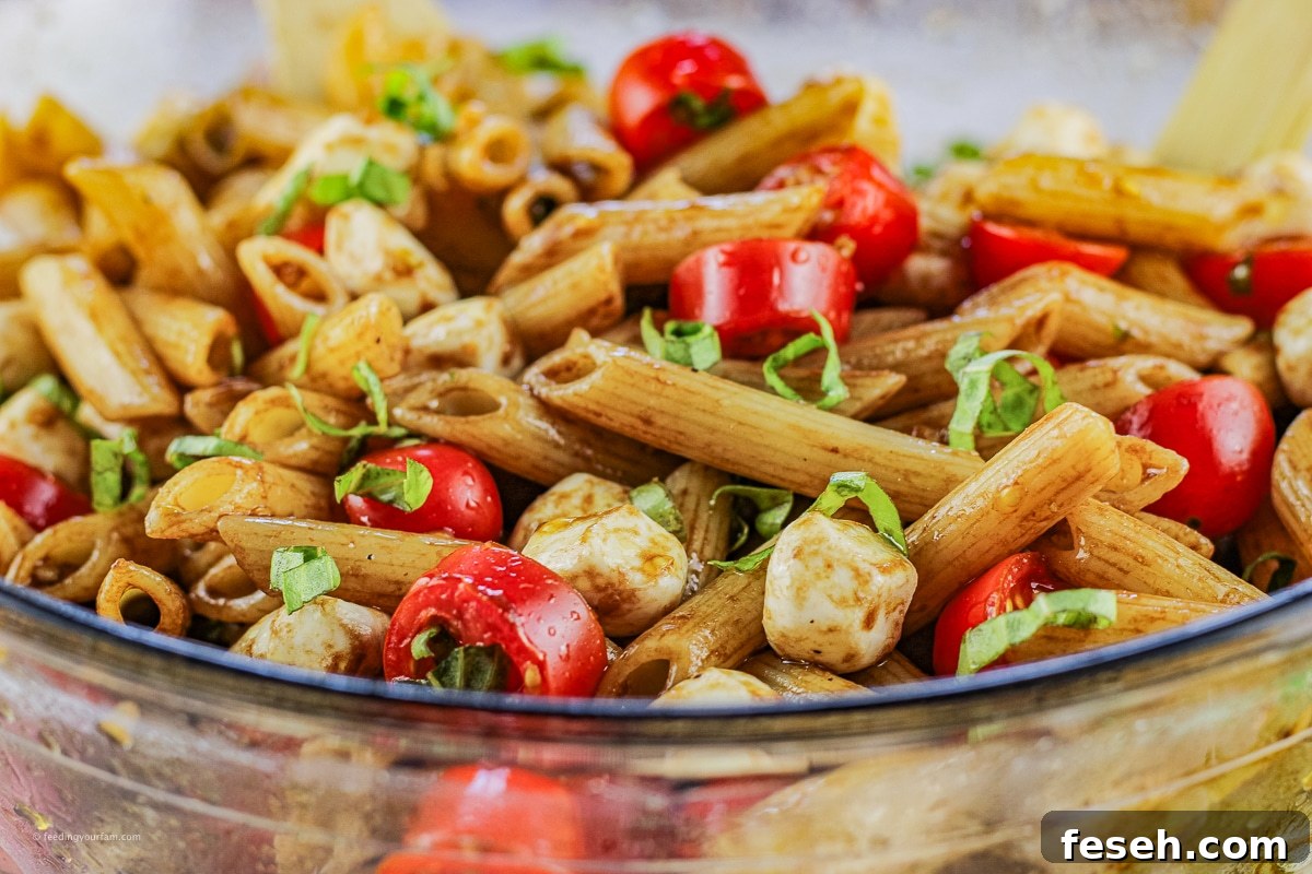 pasta salad made with penne pasta, sliced tomatoes and mozzarella cheese balls