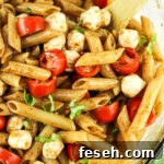 penne pasta salad with mozzarella pearls, tomatoes and basil in a balsamic dressing