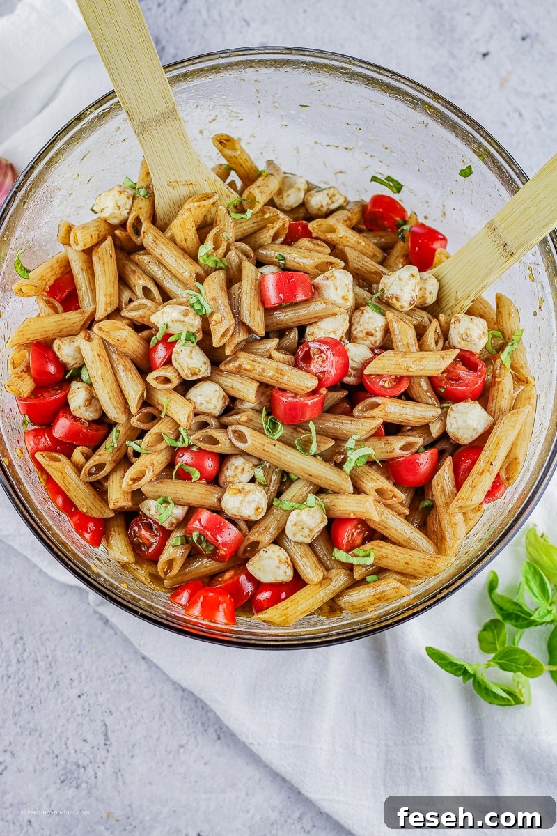 pasta salad made with penne pasta, sliced tomatoes, mozzarella and fresh basil