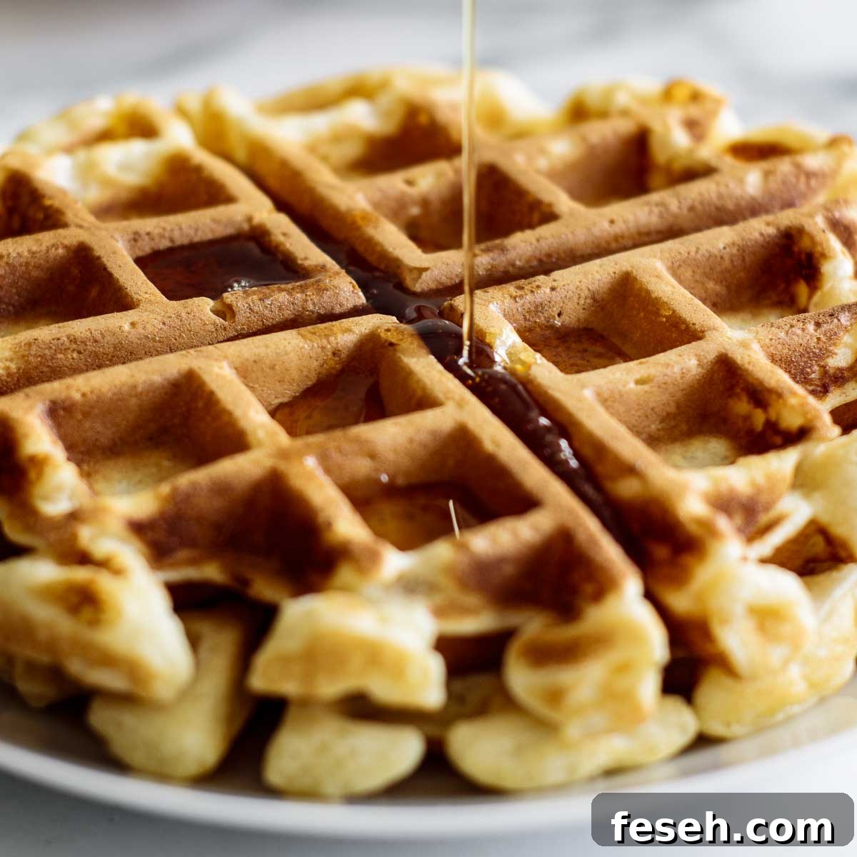 Maple syrup pouring over waffle disk.