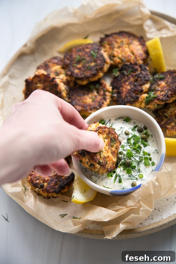 hand dipping pan fried easy canned salmon cakes in sauce