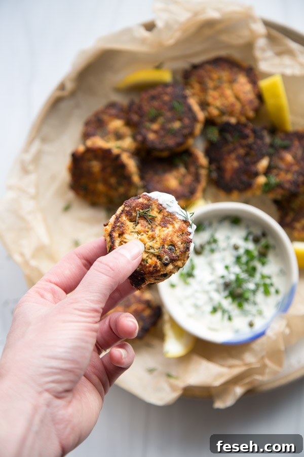 Hand holding pan fried canned salmon patties with easy dipping sauce