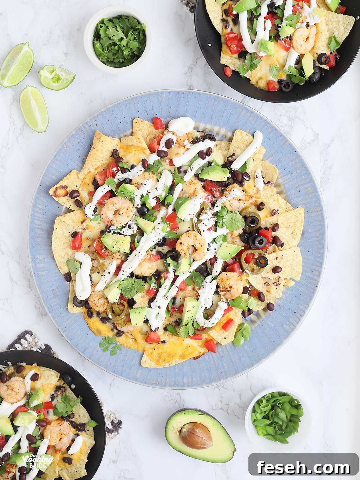 overhead shot of a large blue platter of shrimp nachos with two black bowls with individual servings of nachos to the side