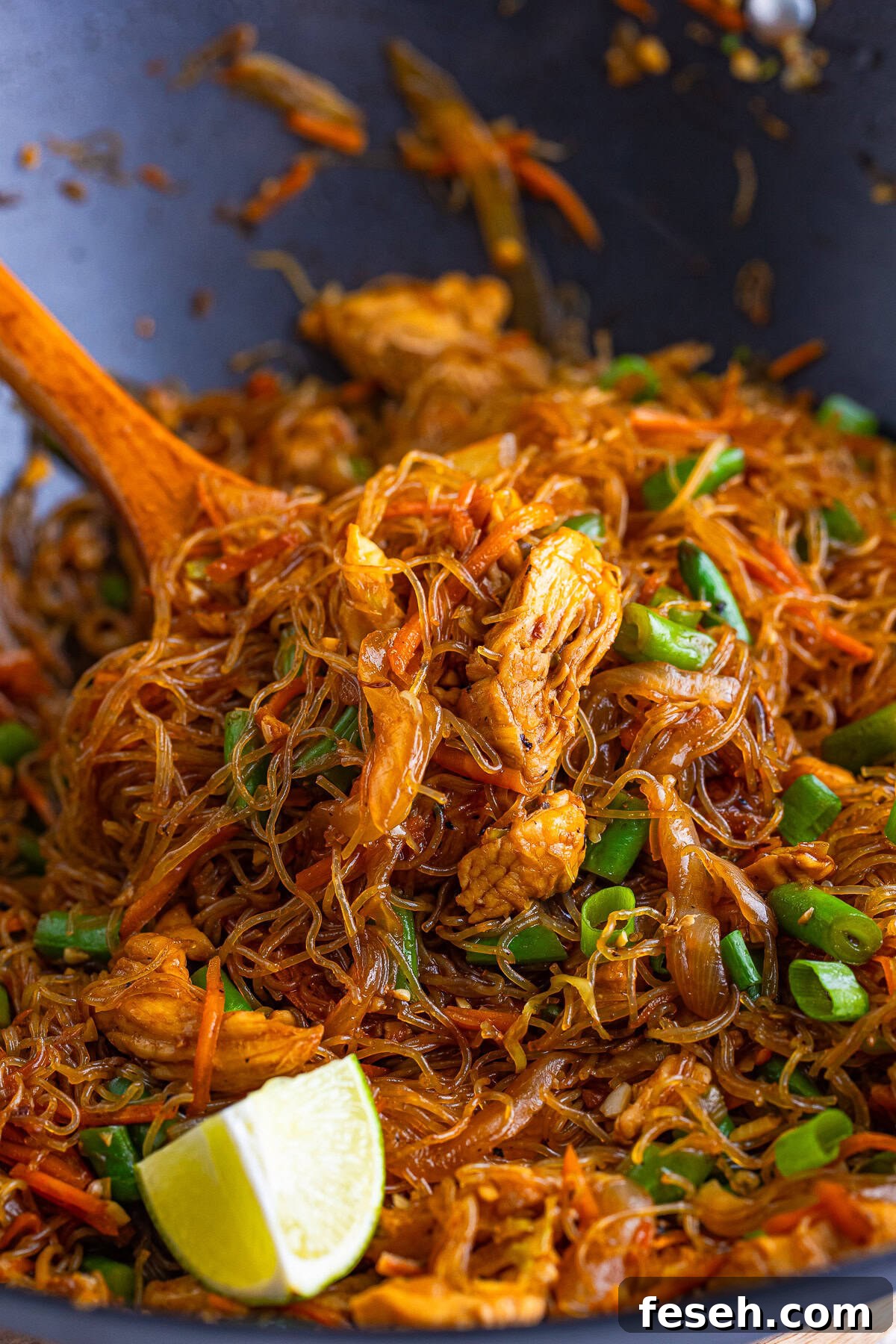 Pancit in a wok with a spatula holding it up