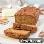 sliced paleo pumpkin bread sitting on a piece of parchment paper with butter in the background