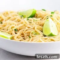 Noodles and a lime wedge on a white plate