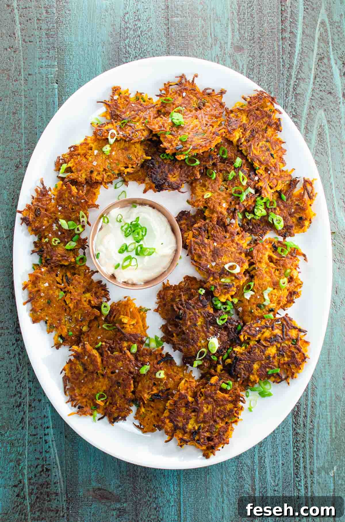 sweet potato latkes on a large platter with sour cream