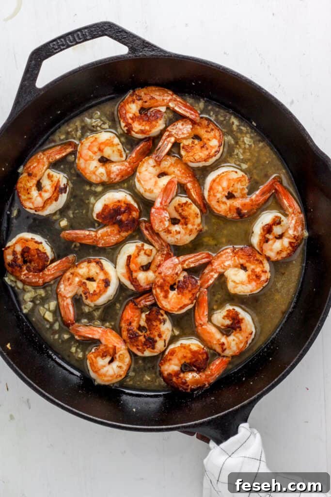 skillet with seared shrimp and a white wine sauce.