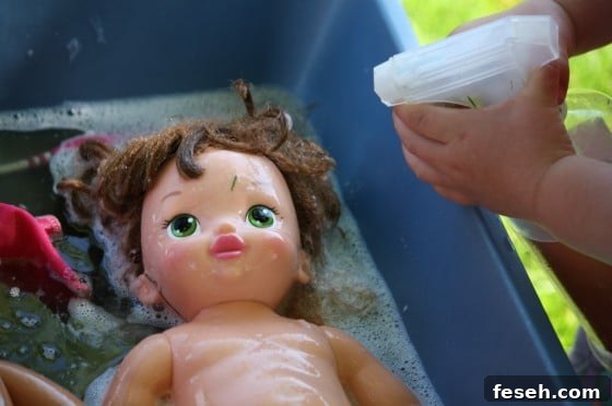 preschooler squirting doll with water from pump bottle